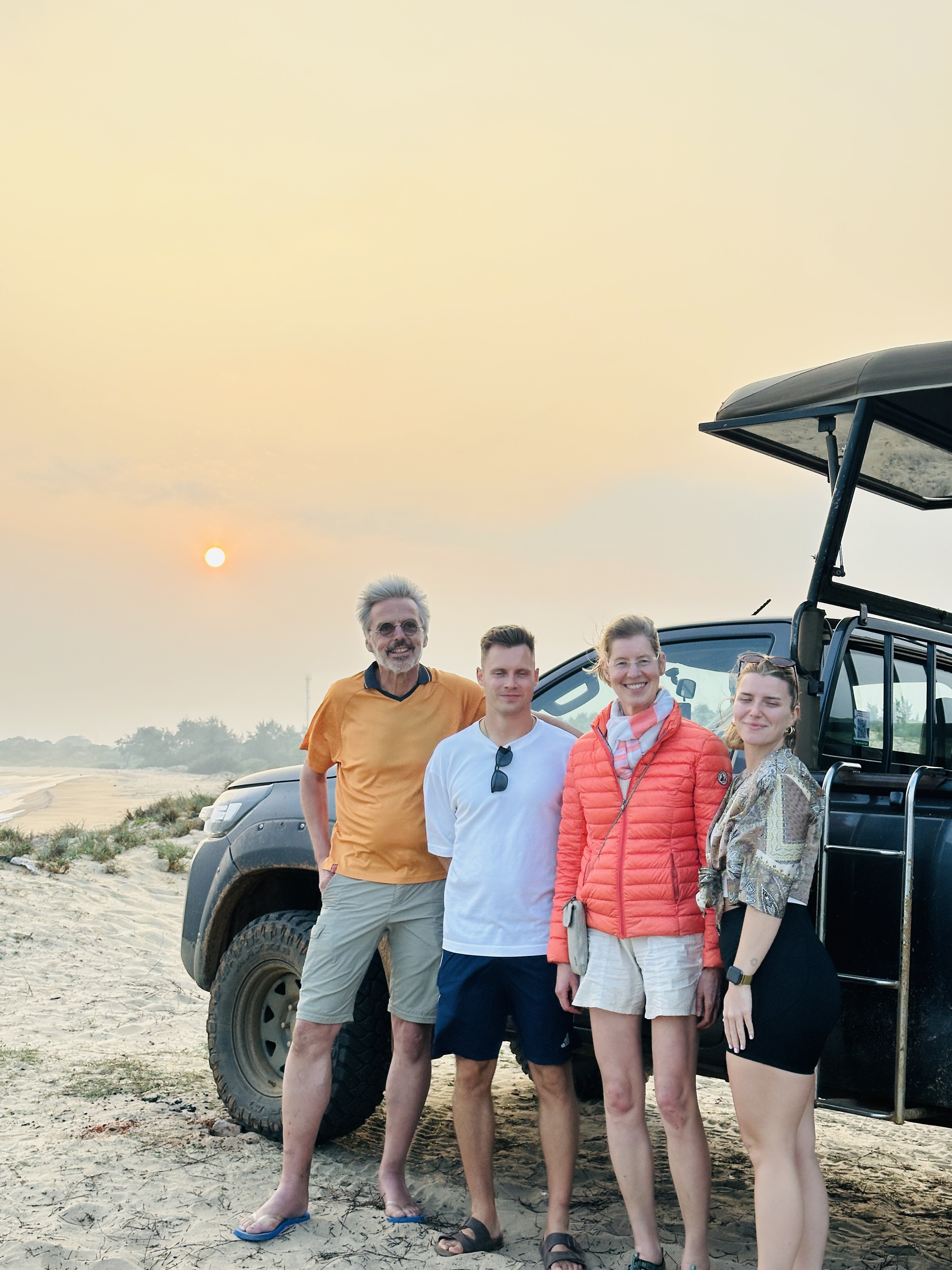 Safari guests beside a jeep at sunset